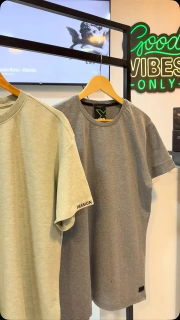 Remeras colgadas en el local con cartel de neón verde